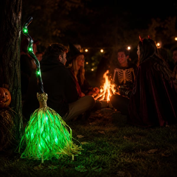 Green glowing witch broom at outdoor Halloween gathering